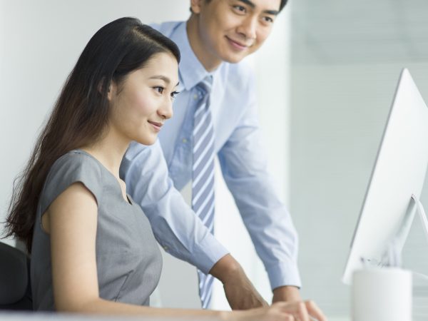 Young Chinese businesswoman and businessman talking in office